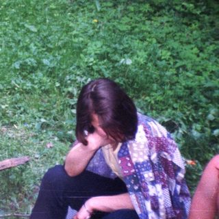 Three people relax outdoors amidst lush greenery and foliage.