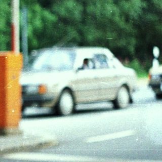 Man stands near a booth, cars visible in the background.
