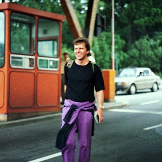 Man stands near a booth, cars visible in the background.