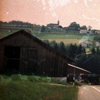 Rural village scene with buildings and a road.