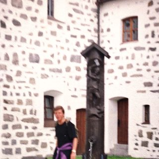 Man stands near a stone monument in front of a building.