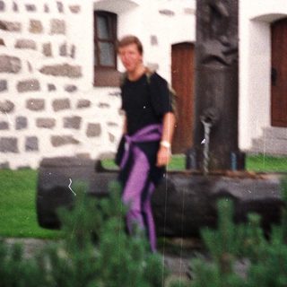 Man stands near a stone monument in front of a building.
