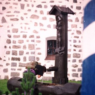 A stone statue stands in front of a stone building.
