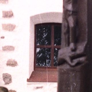 A stone statue stands in front of a stone building.