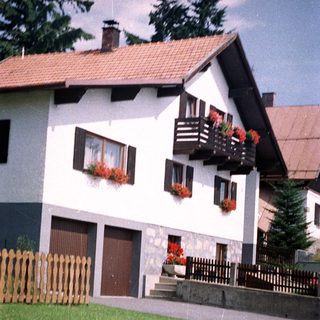 White house with red flowers and a tiled roof.