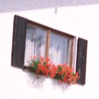 White house with red flowers and a tiled roof.