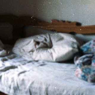 Disheveled bed in a dimly lit, rustic room.