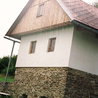 Stone and wood building with rain, barrels visible.