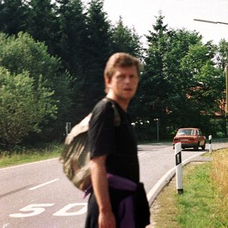 Person walking on road with street signs and building.