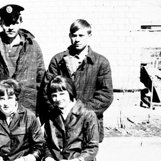 Group of young people posing outdoors near a building.