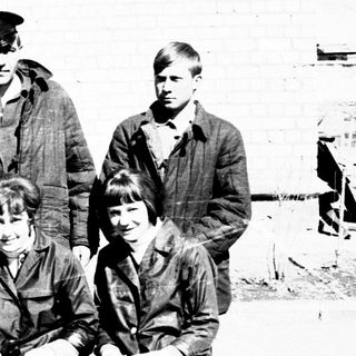 Group of young people posing outdoors, seated on a bench.