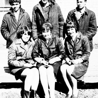 Group of young people posing outdoors, seated on a bench.