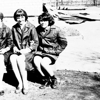 Group of people seated outdoors, possibly in a uniform.