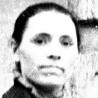 Woman stands outside a building, wearing a long coat.