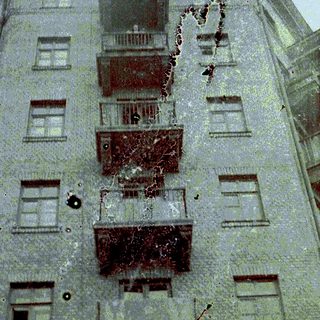 Building with visible damage, likely from gunfire or explosions.