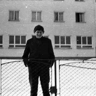 Young boy standing in snow, building in background.