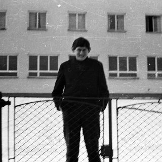 Young boy standing in snow, building in background.