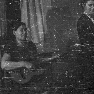 A man and woman stand, another person sits nearby.