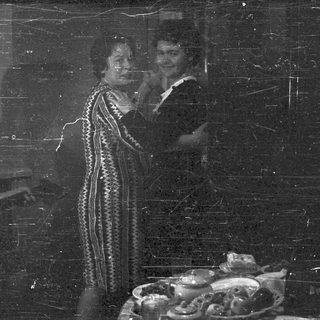Here's a brief summary of the image: Three people stand near a table with decorative items.