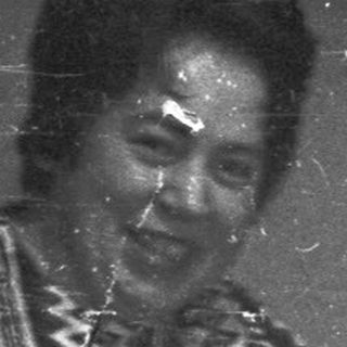 Woman holding object, another person in background, vintage photo.