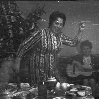 Woman holding object, another person in background, vintage photo.