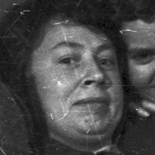 Here's a brief summary of the image: Two people sit close, smiling in a room.