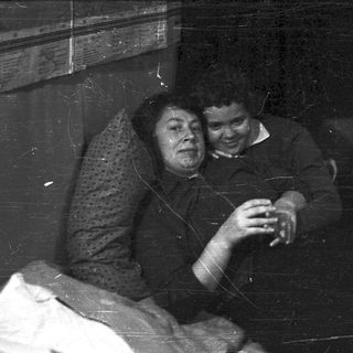 Here's a brief summary of the image: Two people sit close, smiling in a room.