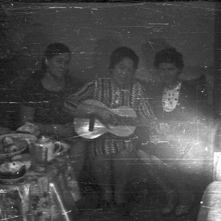 Three people playing musical instruments indoors, vintage photograph.
