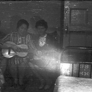 Three people playing musical instruments indoors, vintage photograph.