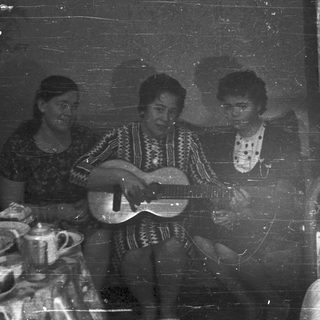 Three people playing music indoors, vintage black and white photo.