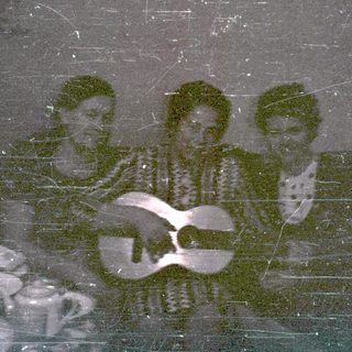 Three men sit playing instruments in a room.