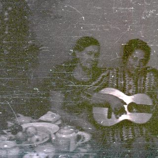 Three men sit playing instruments in a room.