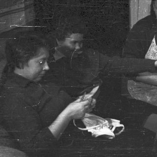 Two women working with fabric in a dark room.