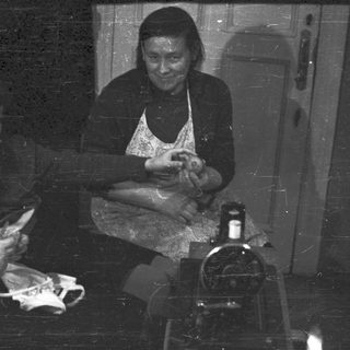 Two women working with fabric in a dark room.