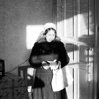 Woman stands in a room, illuminated by strong light.