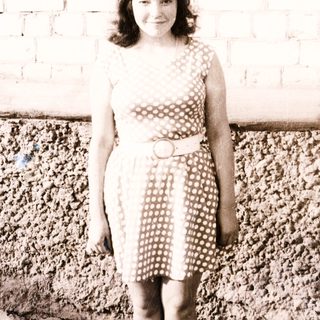 Young girl stands in a polka dot dress outdoors.