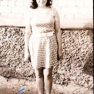 Young girl stands in a polka dot dress outdoors.