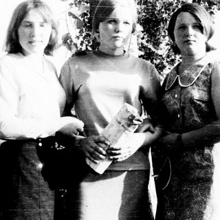 Three young women standing outdoors in a black and white photo.