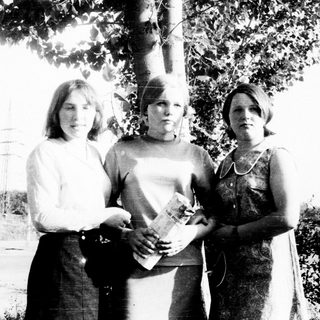 Three young women standing outdoors in a black and white photo.