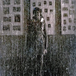 Man stands before a building, obscured by scratches and damage.