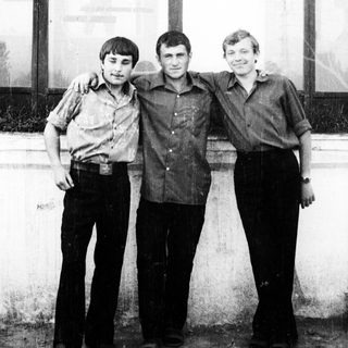 Three men stand together, arm around each other.