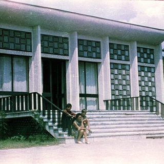People sit on steps in front of a modern building.