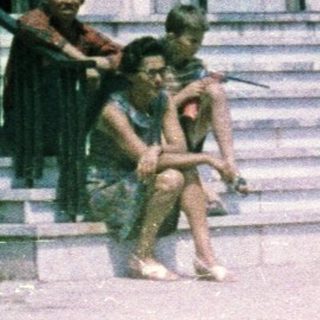 People sit on steps in front of a modern building.
