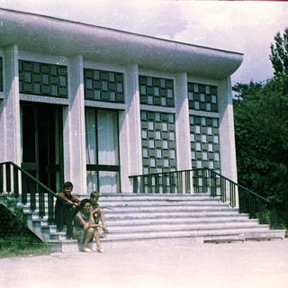 People sit on steps in front of a modern building.