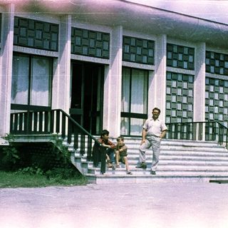 Man and child near building with patterned facade.
