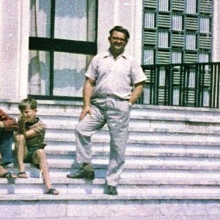 Man and child near building with patterned facade.