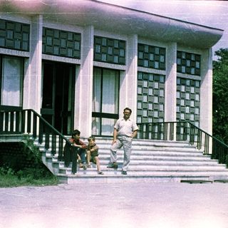 Man and child near building with patterned facade.