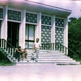Man and child near building with patterned facade.