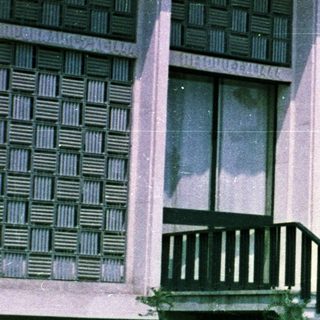 Man and child near building with patterned facade.