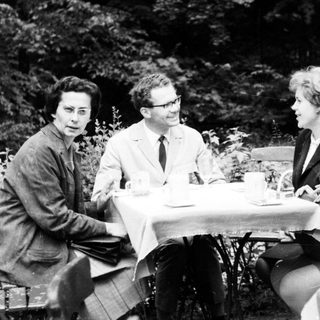 Four people sit at a table outdoors, conversing.
